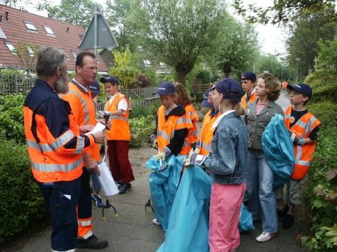 Schoolkinderen in Voorhout krijgen instructies voor het opruimen.
